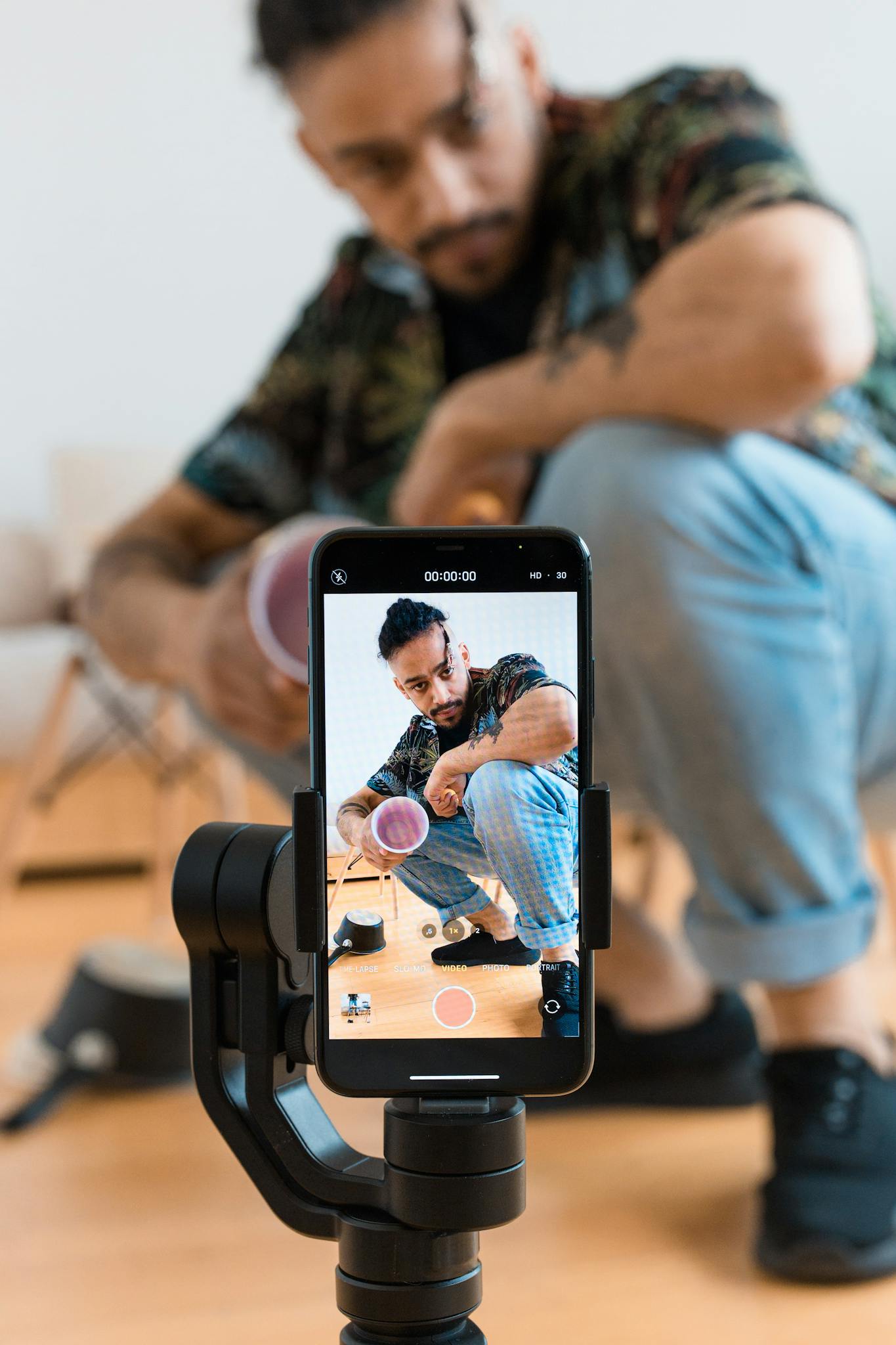 Man recording a creative video using a smartphone tripod, showcasing content creation indoors.